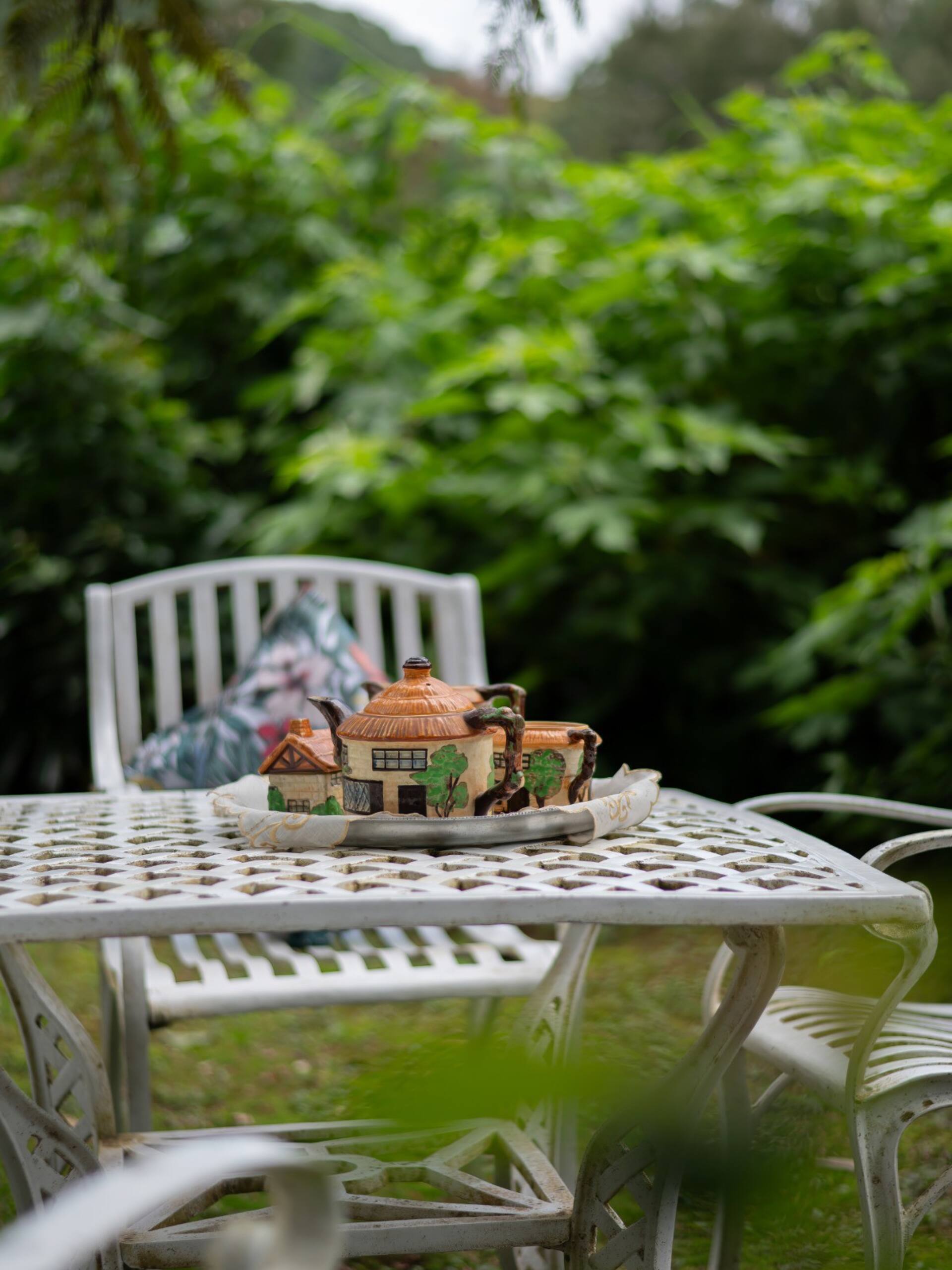 A cottage-shaped tea set on a white garden table at Selwood Cottage